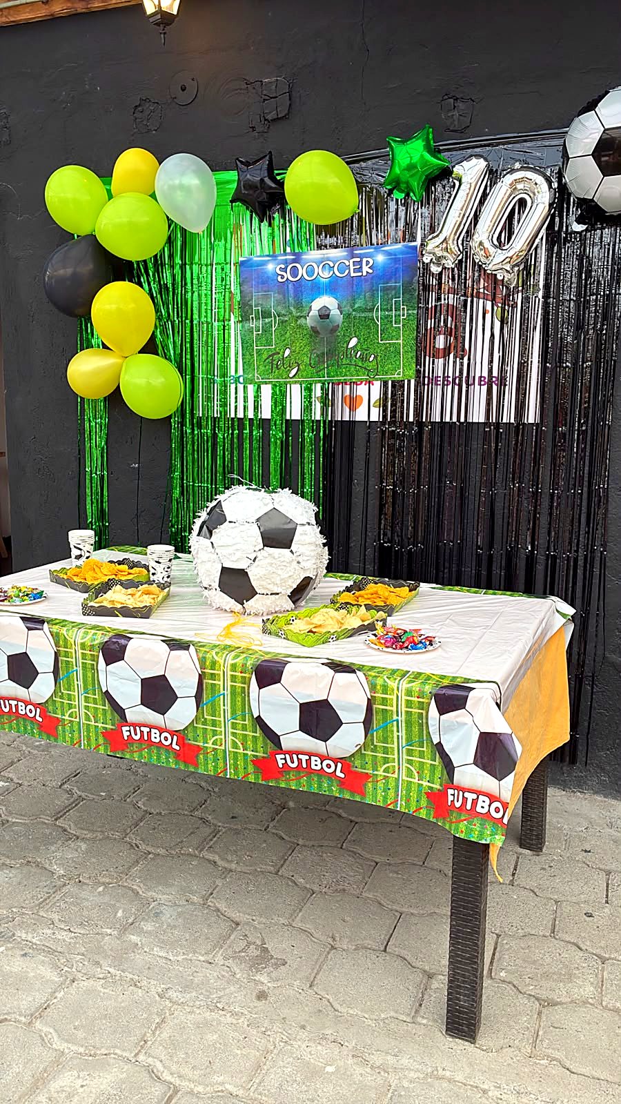 Mesa de cumpleaños montada en Little Moka con globos, mantel temático de fútbol y bocaditos