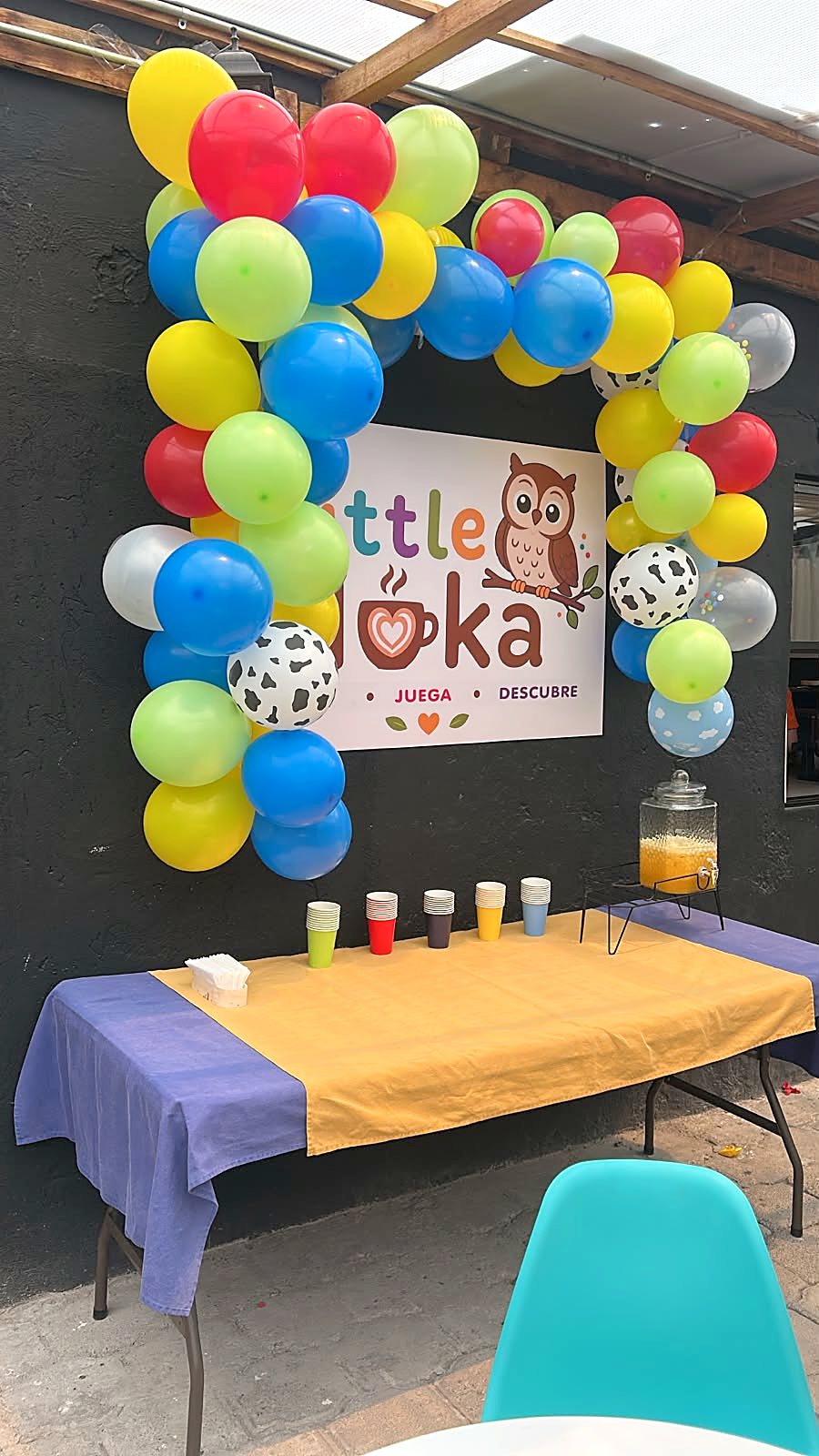 Mesa de cumpleaños montada con un arco de globos de colores y el logo