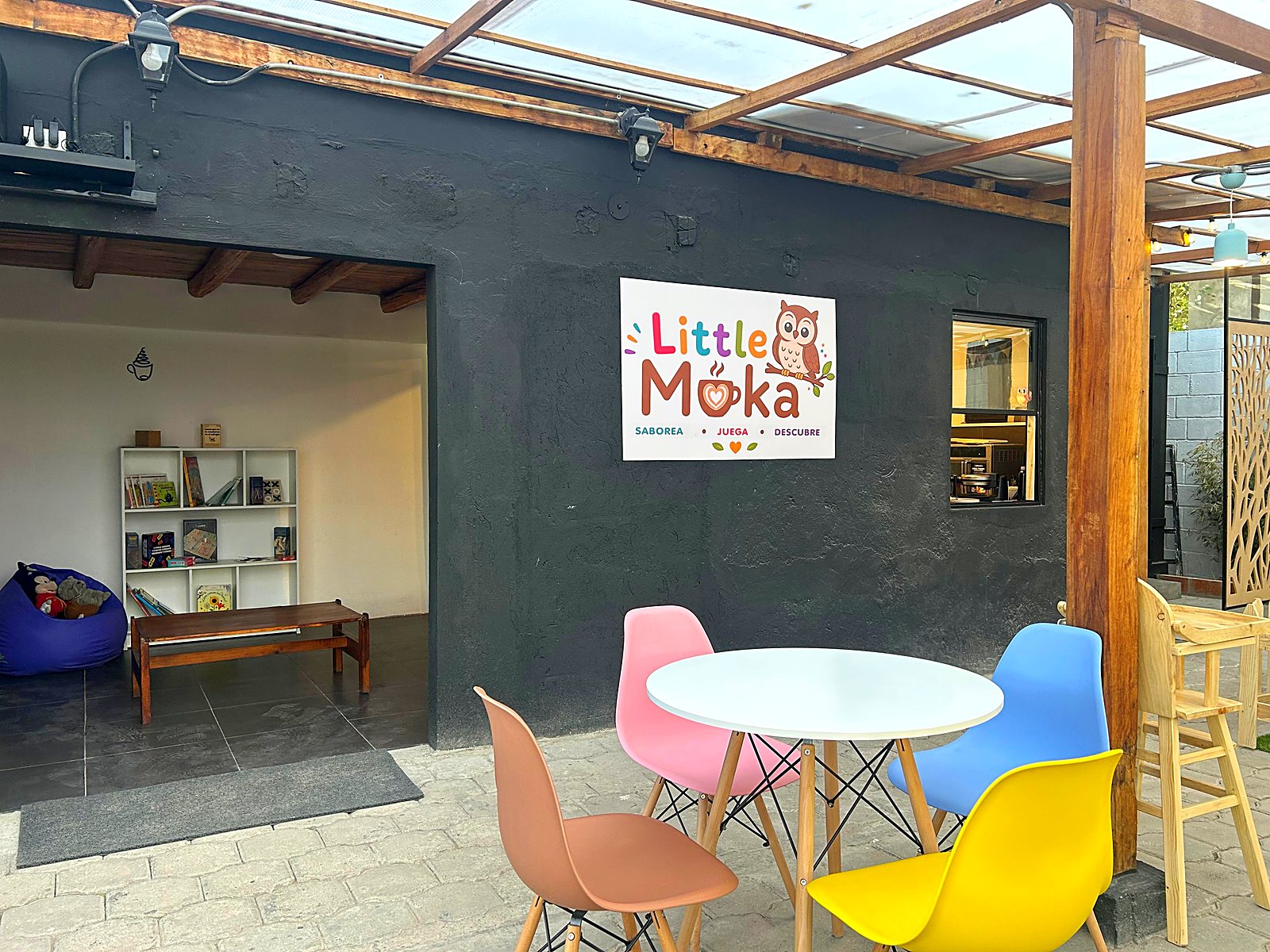 Patio de entrada de Little Moka, con el letrero, mesas y sillas de colores